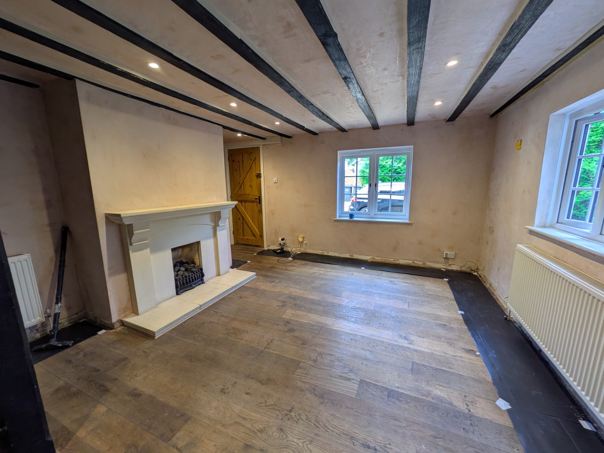 Dining room before renovation with damaged plaster walls, uneven surfaces, old flooring and exposed beams in a dated UK home