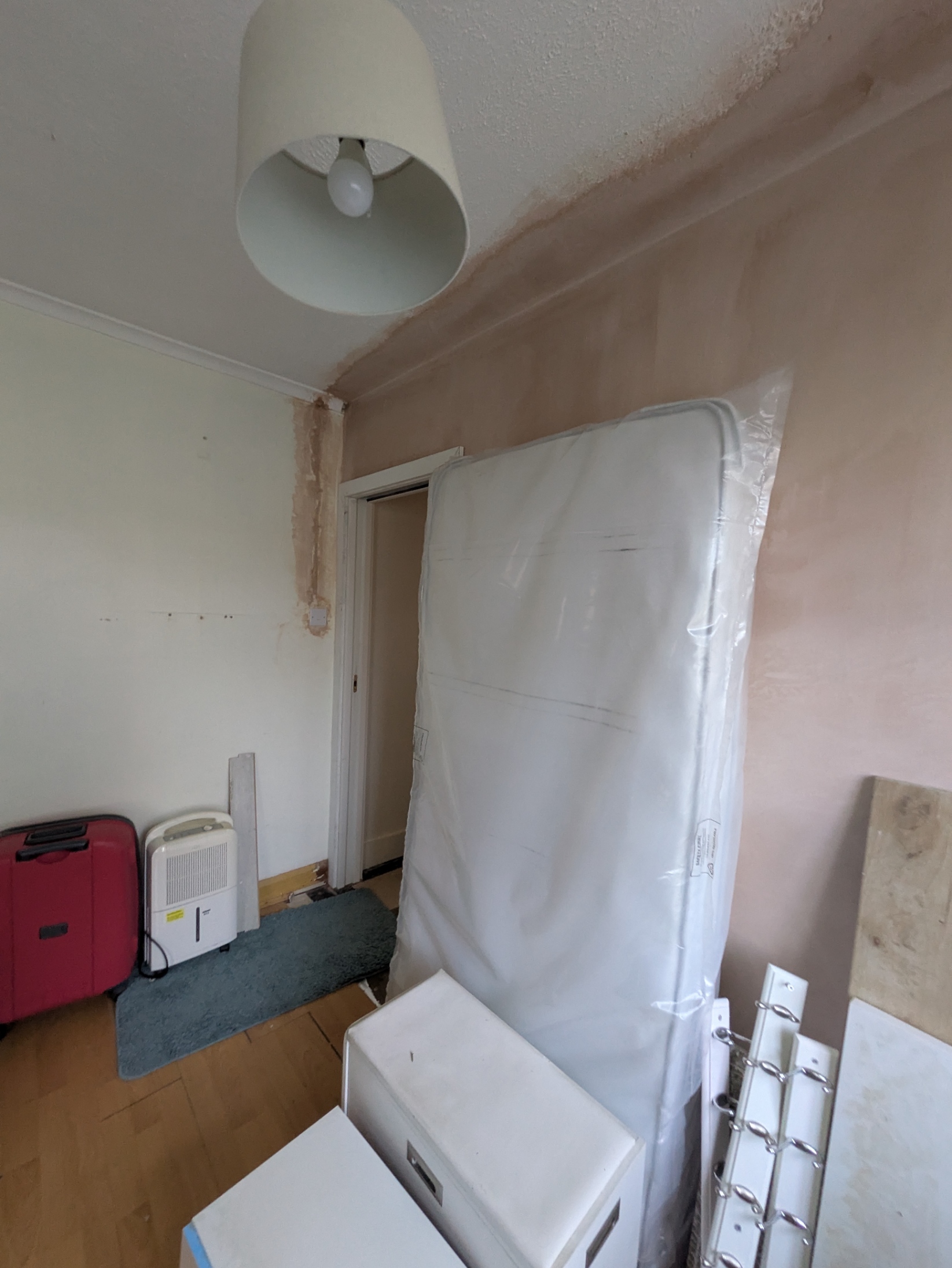 Before room renovation with damaged walls, old flooring and outdated lighting before refurbishment in UK home