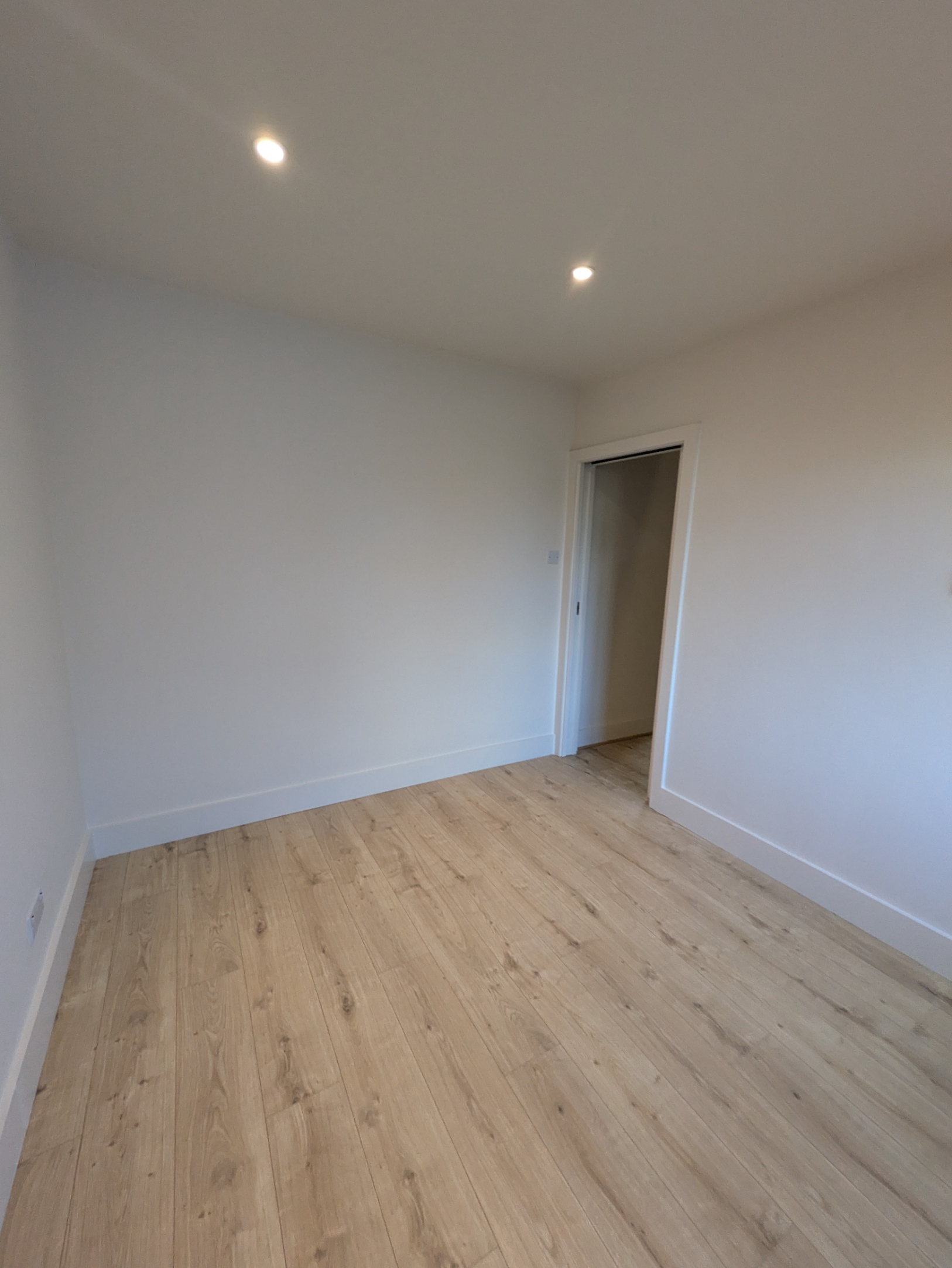 After room renovation with new spotlights, replastered walls, laminate flooring and modern painted finish in UK home