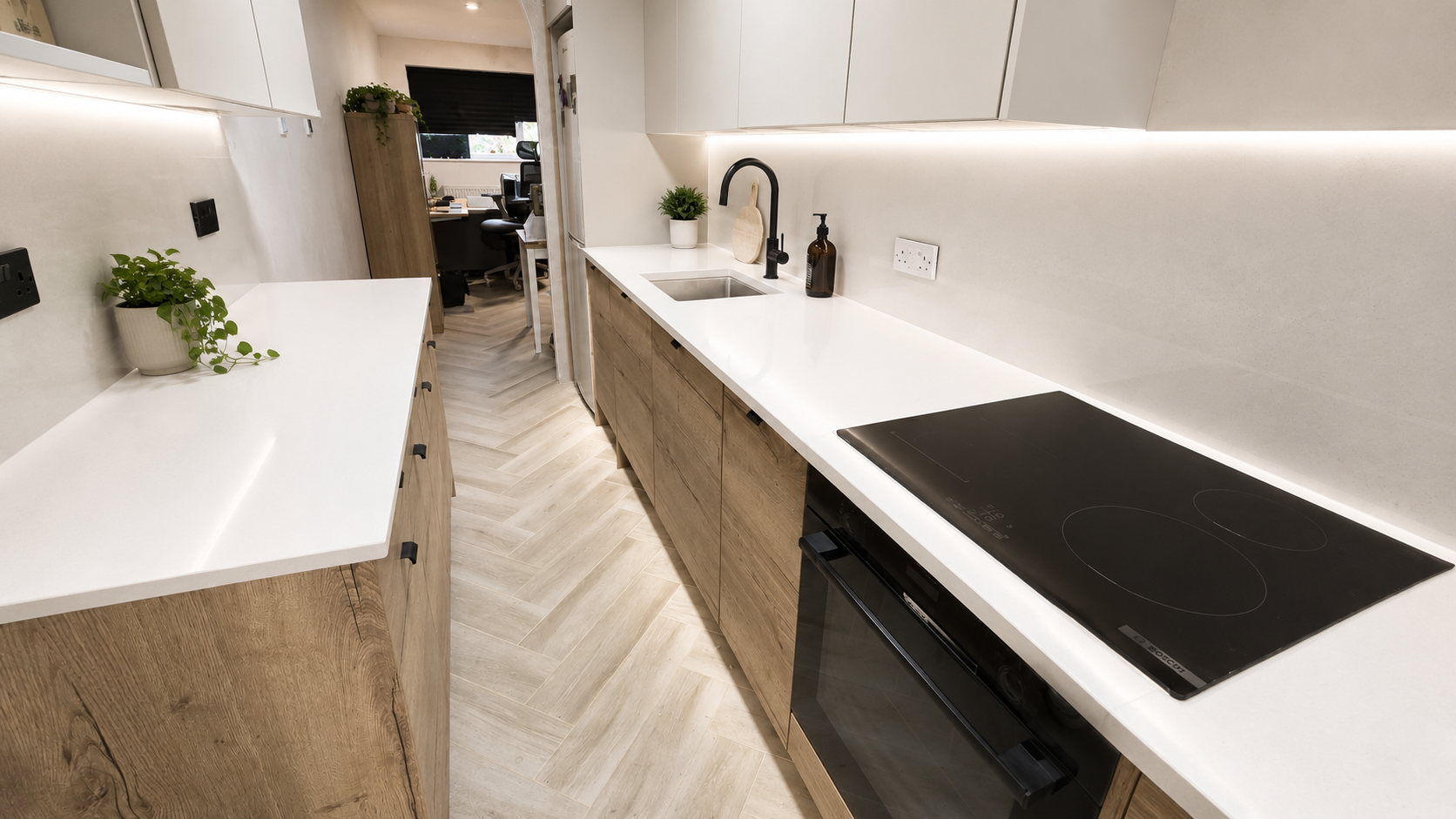 Modern galley kitchen refurbishment in Surrey with quartz worktops, wood-effect cabinets, herringbone flooring and integrated appliances